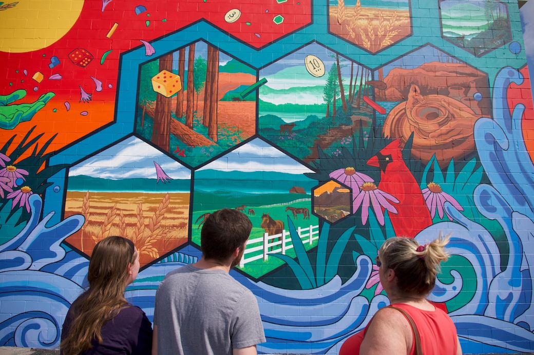 People standing in front of a CATAN mural made of hexagons